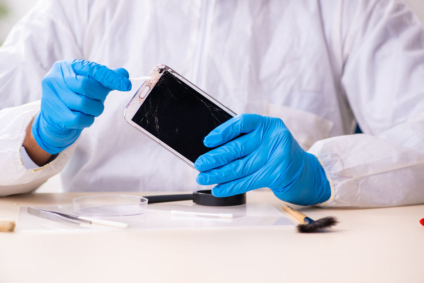 A digital forensics specialist carefully conducting an analysis of a smartphone.