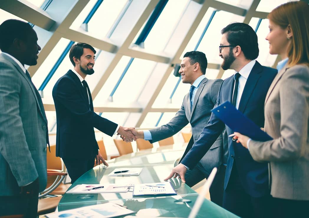 Business executives shake hands during an Acquisition business merger after seeing results from an Investigative Due Diligence Review.