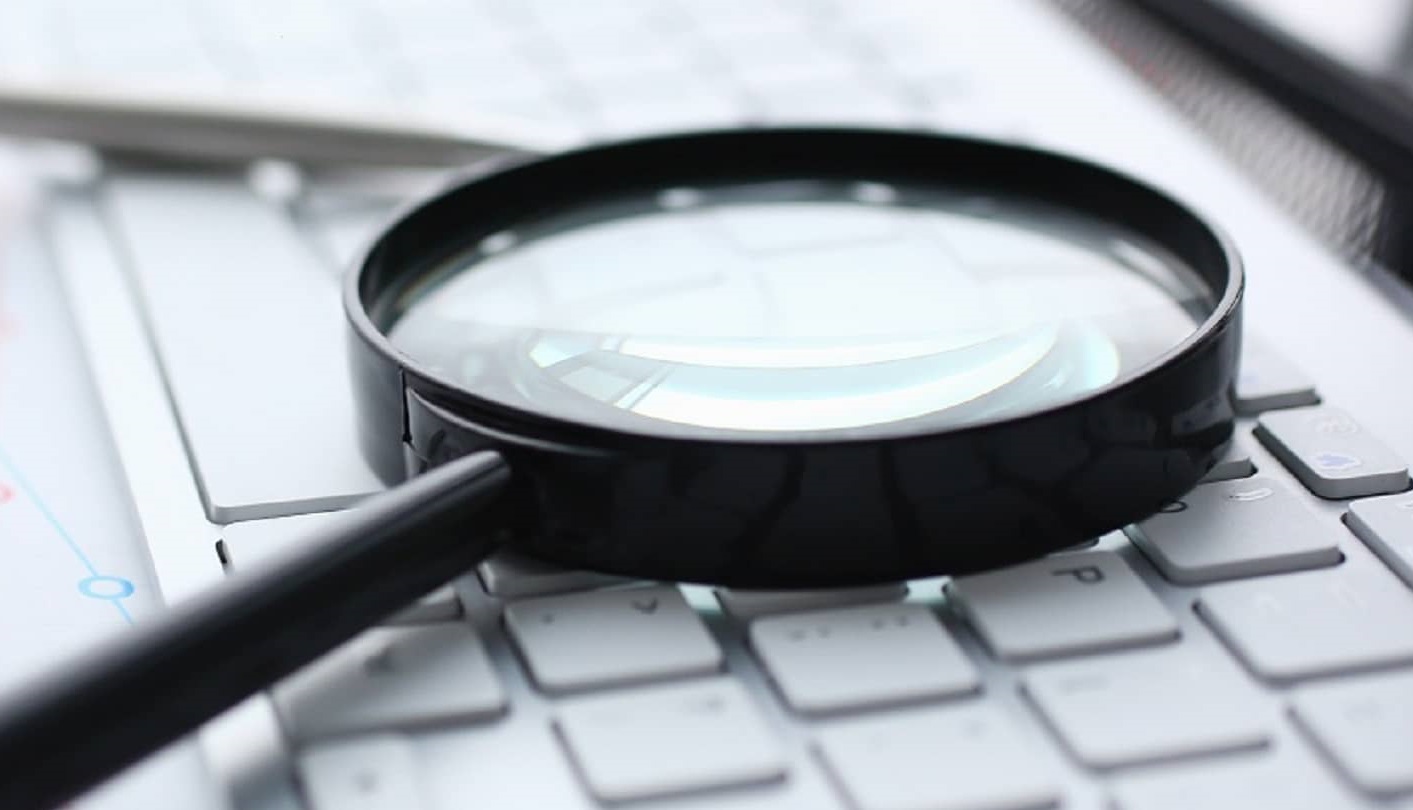 Private Investigator Vancouver Skip Tracing service for Locating Individuals as a magnifying glass lays on a keyboard symbolizing the search.